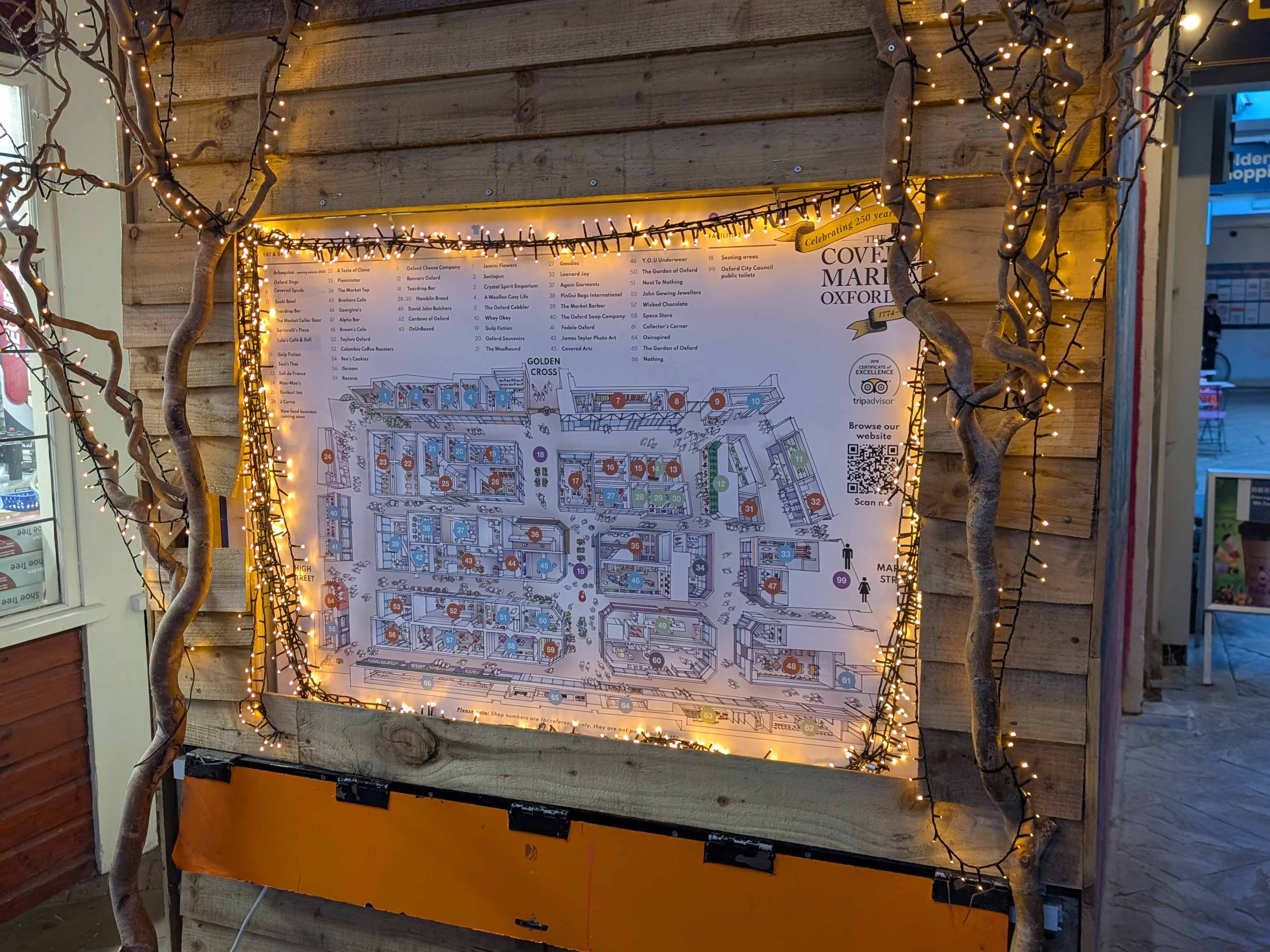 A photo of an Oxford city map in a wooden hut surrounded by fairy lights