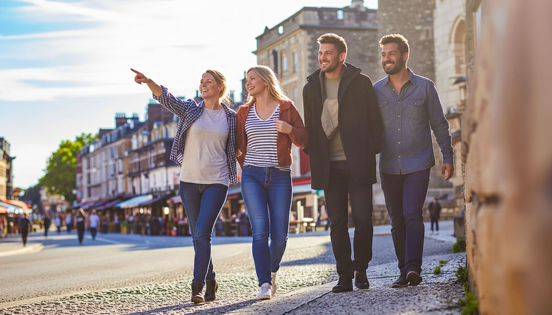 Four people walking through a city, one pointing ahead, representing help and guidance.